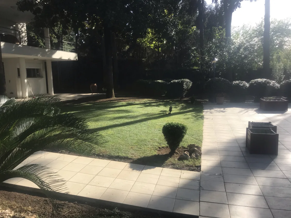 Tuzla’daki özel villa bahçesinde ağaç gölgeleri arasındaki çim alan ve biçimlendirilmiş çalılar